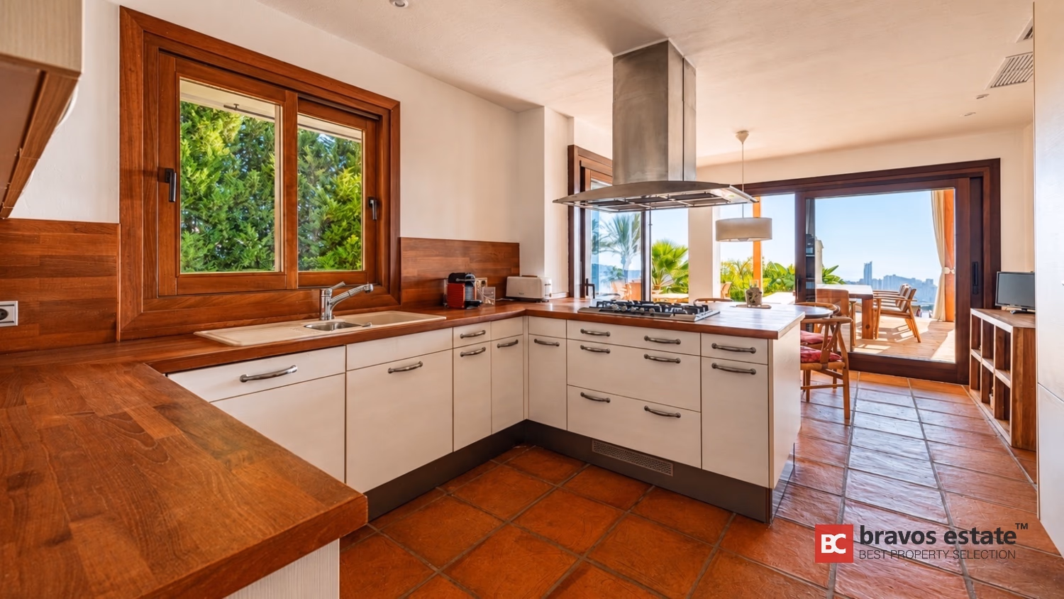 Кухня Villa Ibiza со столешницей из массива дерева, белыми шкафами, техникой Siemens и центральным островом