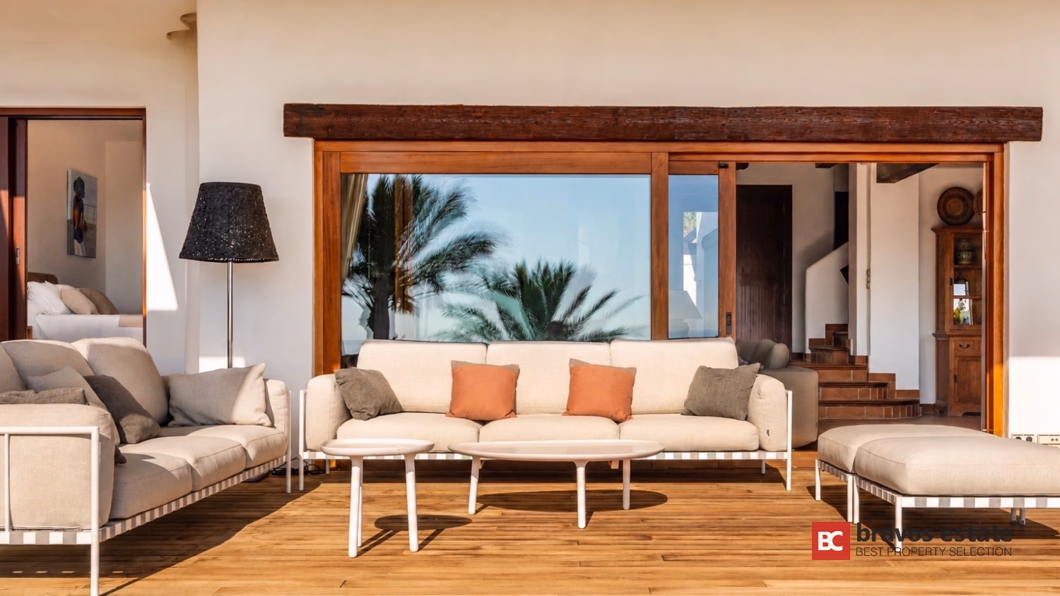 Гостиная Villa Ibiza с кремовыми диванами, открытыми деревянными балками и раздвижными дверями на террасу