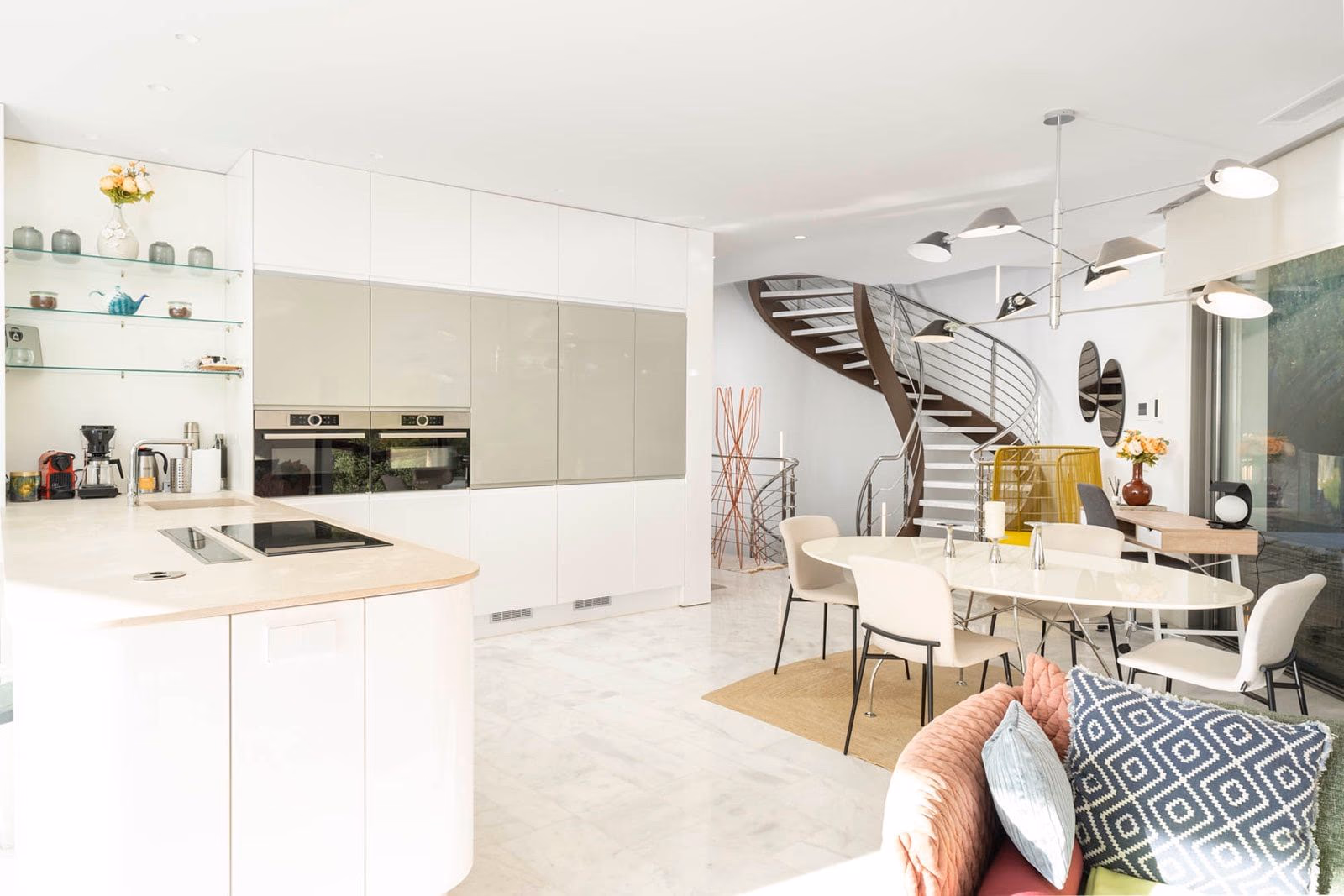 Open living-dining-kitchen with sculptural spiral staircase