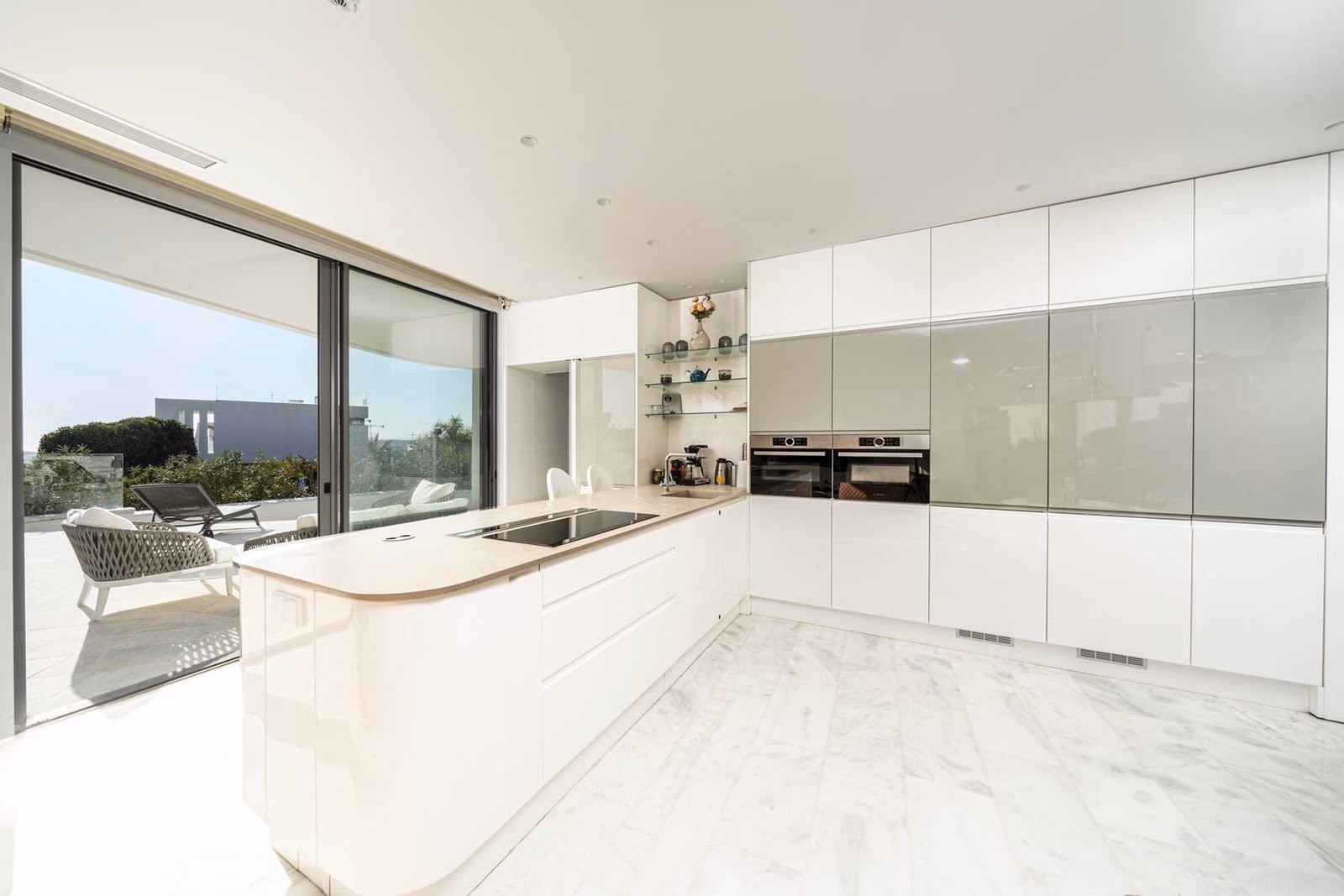 White kitchen with island and full-height sliding doors to terrace