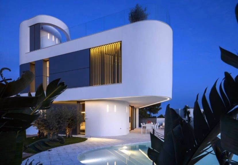 Blue-hour exterior with illuminated pool and curved white facade