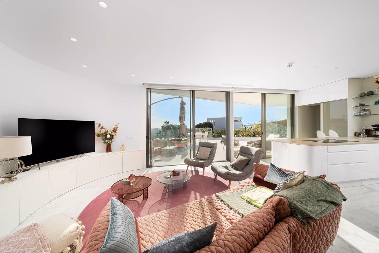 Living room with curved wall, soft rug and view to terrace