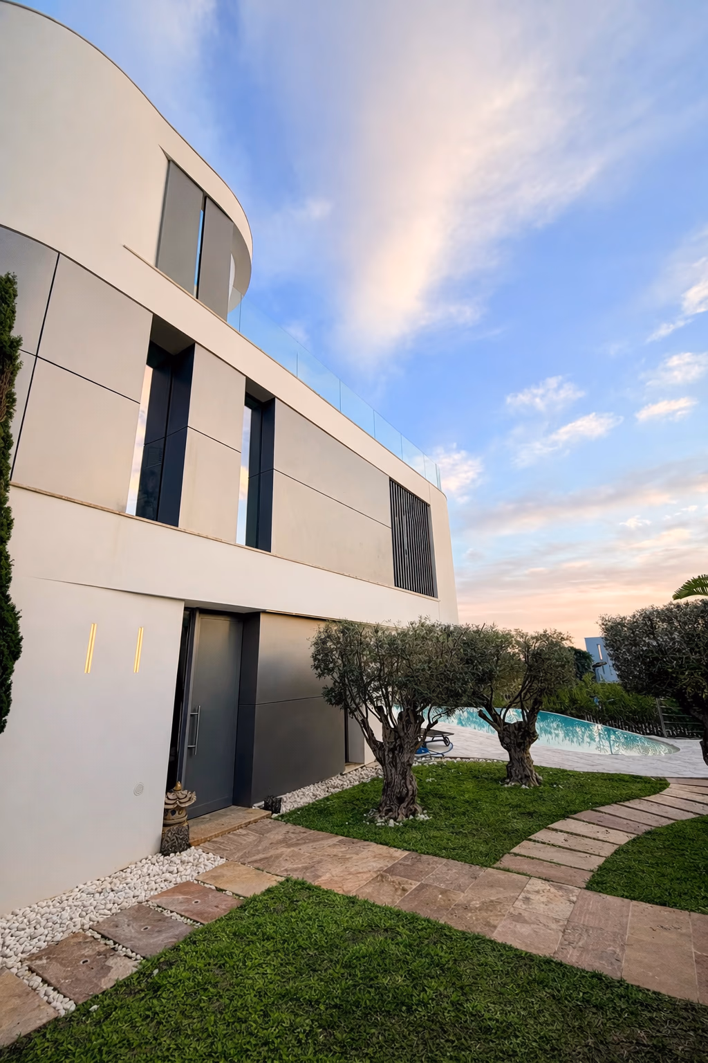 Sunset exterior with olive trees and curved white wing