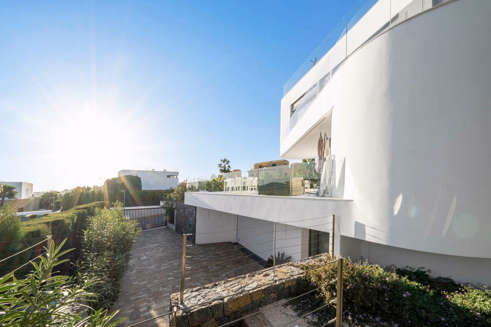 Side walkway with curved white facade and natural stone retaining wall