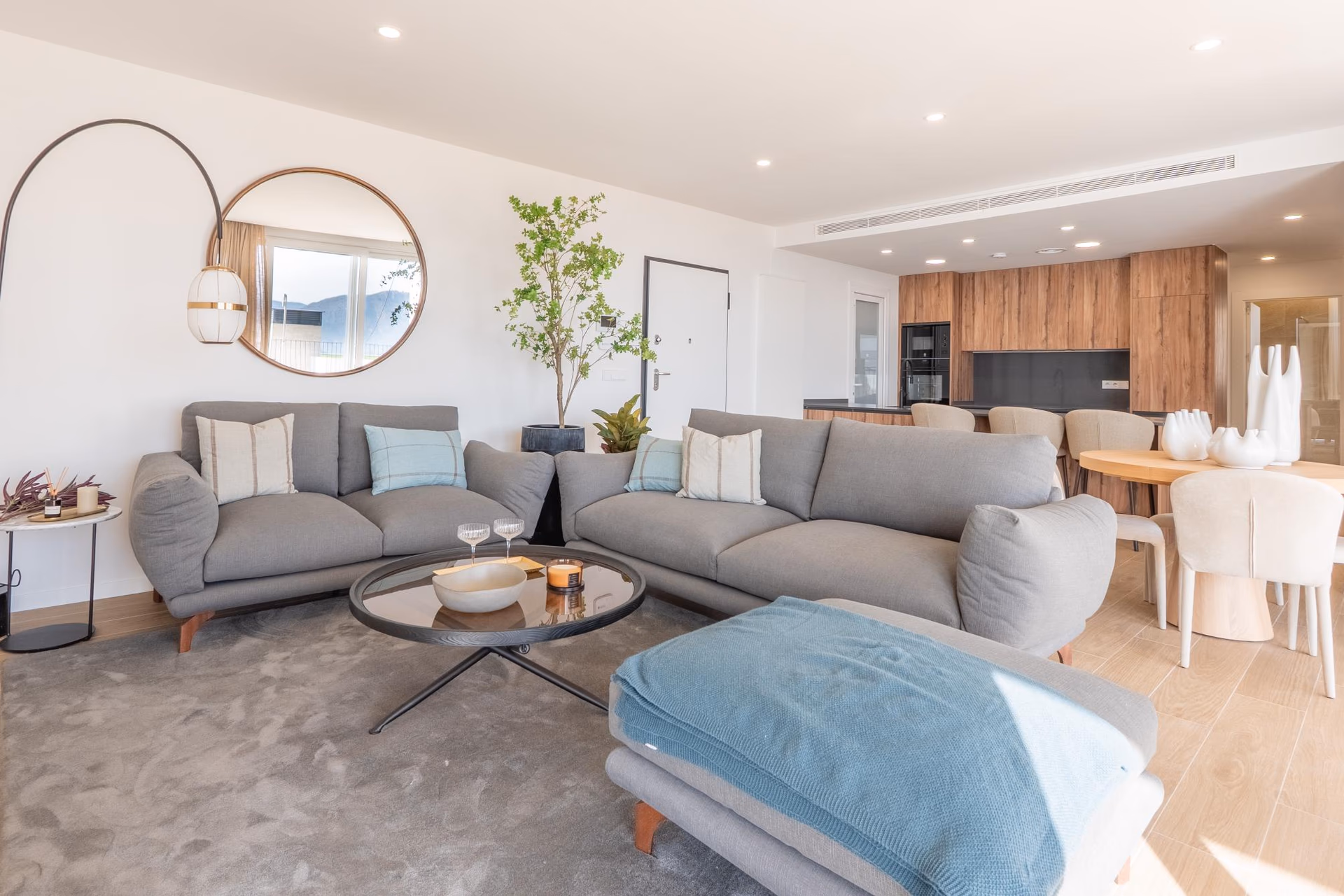 Living room of the show villa with grey sofa and glazed wall to the garden