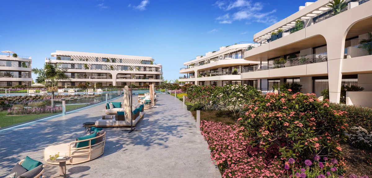 Прогулочная зона у бассейна с лежаками и цветущими посадками в Naya Residences