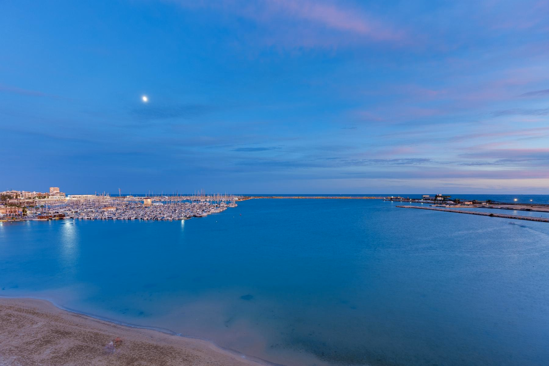 Вид с пятого этажа на Playa del Acequión, порт Торревьехи и залив в сумерках