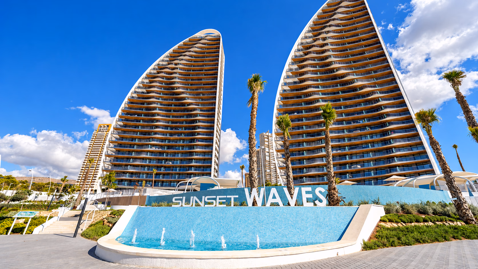 Two wave-shaped towers above the entrance water feature and the complex sign