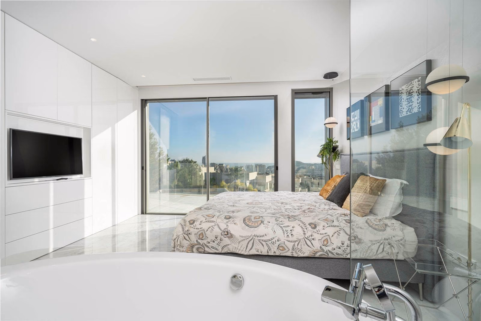 Bedroom with freestanding bathtub and sea view through floor-to-ceiling glass